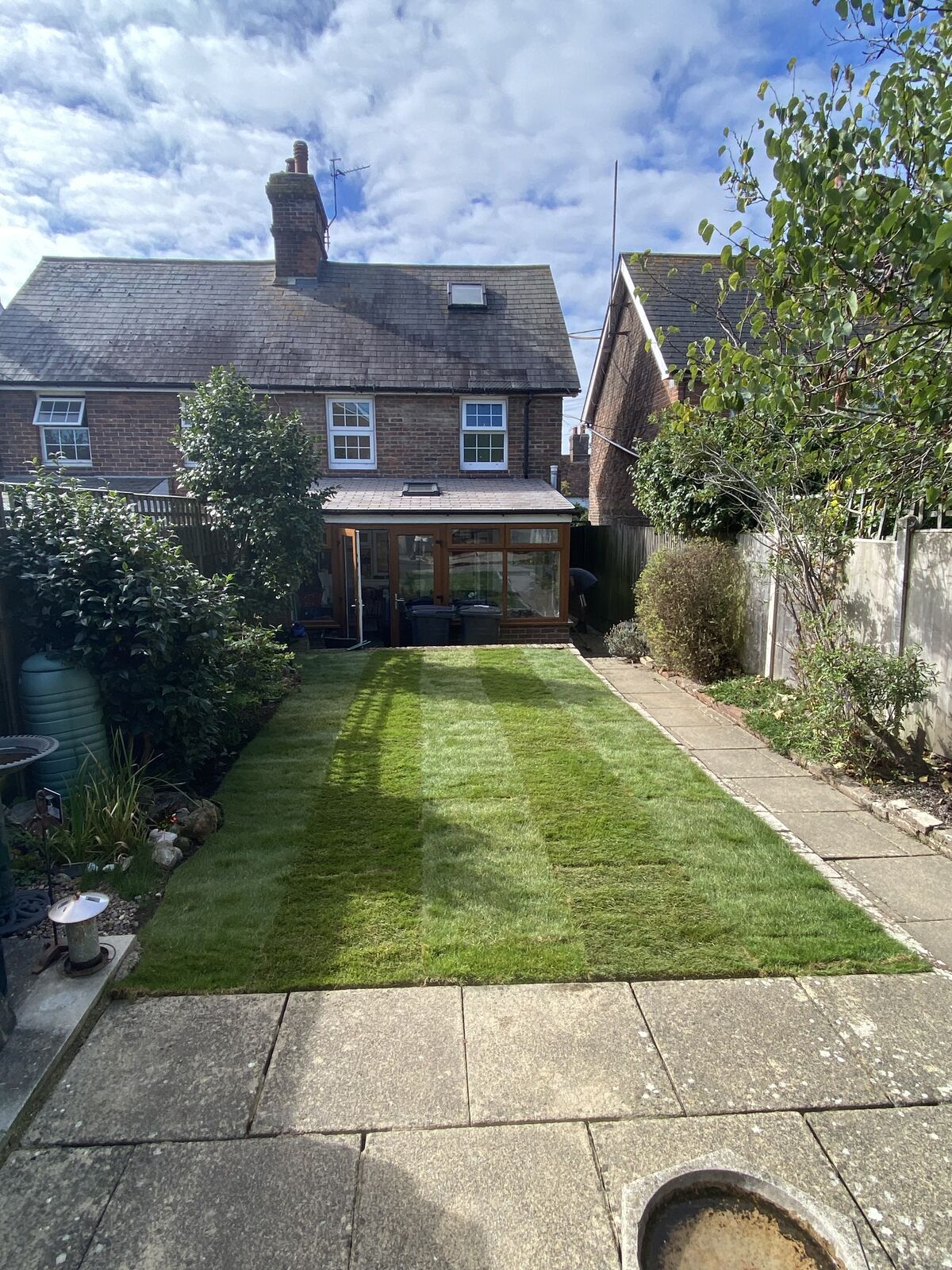 The same small back garden finished with a neat new lawn between the patio paths