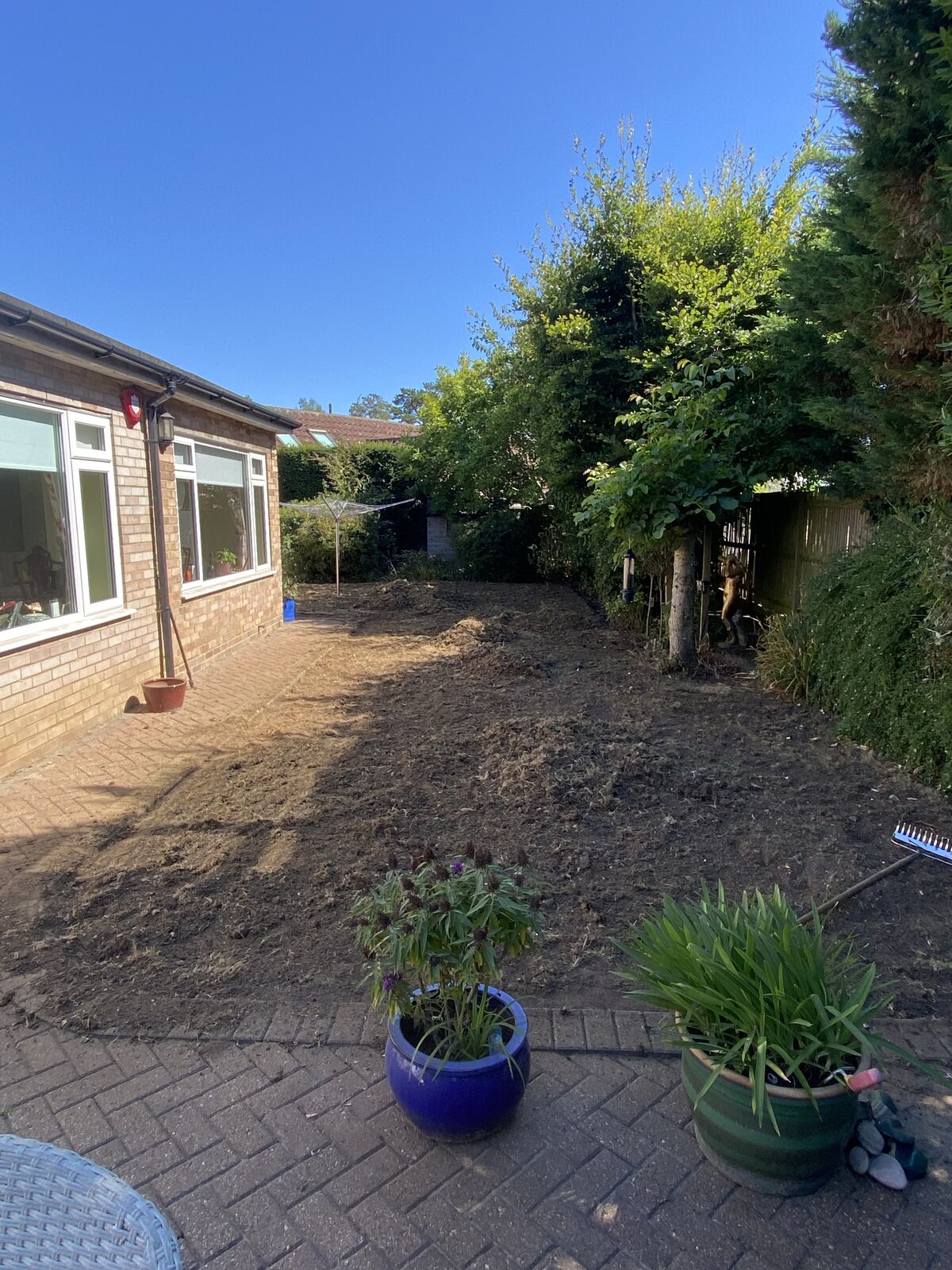Side garden beside a bungalow stripped back to bare soil, ready for new turf