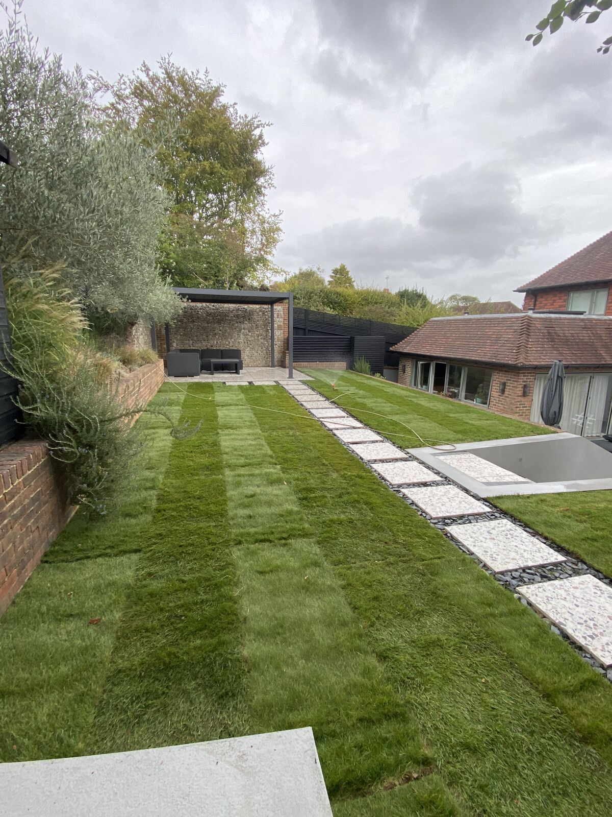 The same long garden finished with a freshly laid striped lawn beside the stepping stone path